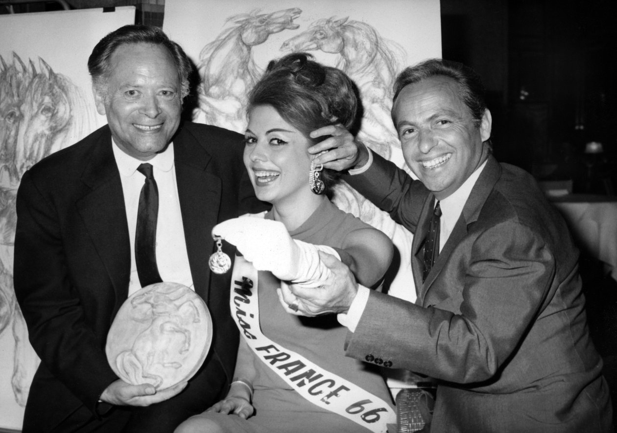 Rene Bollinger (z lewej) i Guy Lux Entourent Monique Boucher „Miss France”, której właśnie wręczyli brelok „Talisman Du Turfiste” podczas otwarcia Bollingers Canvas 12 lipca 1966 r. autorstwa Unknown
