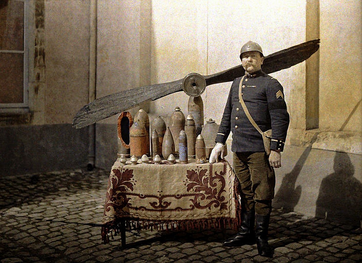 Francuski żołnierz przy stole z niemieckimi granatami i śmigłem lotniczym, Reims, Marne, 1917 (autochrome) autorstwa Fernand Cuville