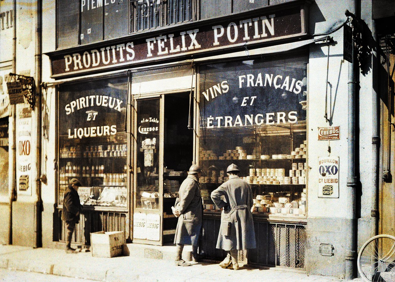 Dwóch francuskich żołnierzy i chłopiec przed sklepem monopolowym Felix Potin na rynku, Reims, Marne, Francja, 1917 (autochrome) autorstwa Fernand Cuville